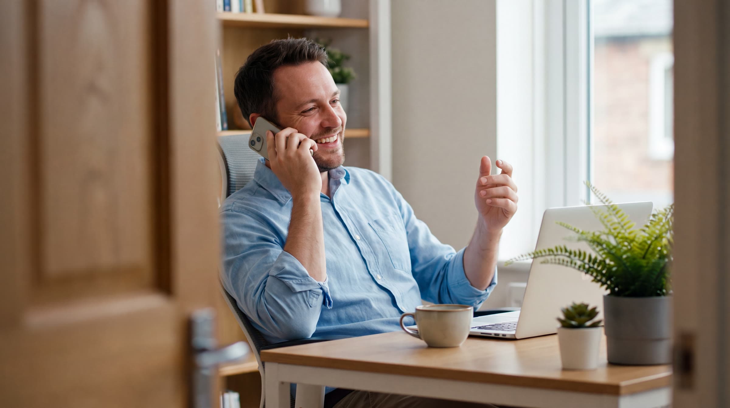 The owner of a cleaning company in their office, smiling on the phone. Illustrative photo.